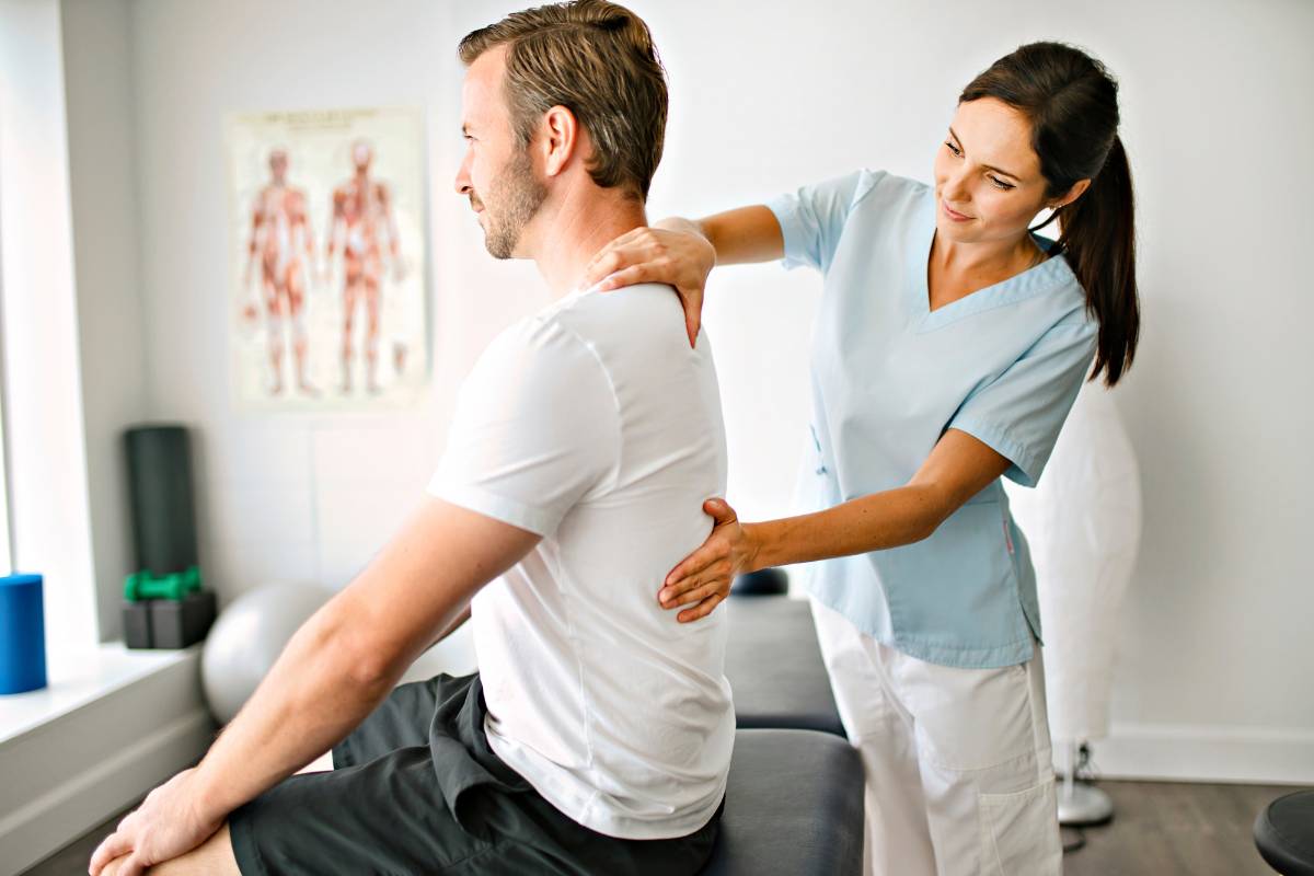 A sports medicine nurse assists a patient with a back injury.