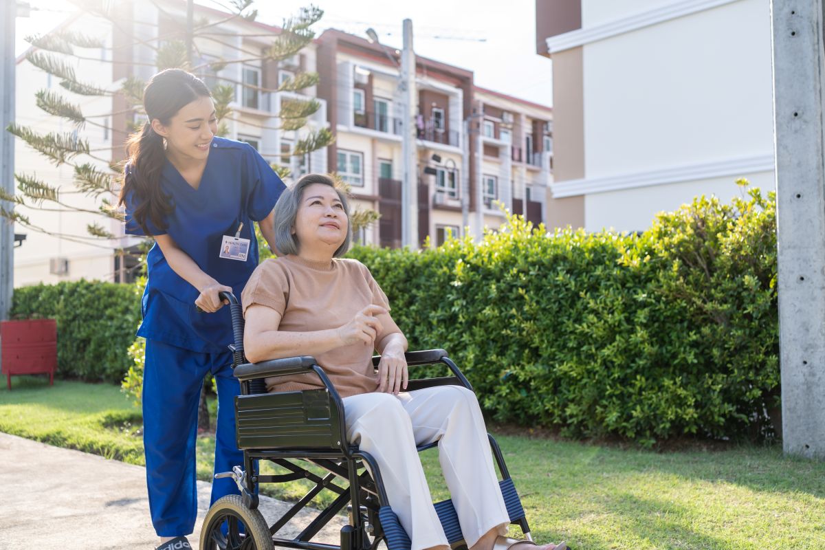 Female STNA transporting female patient in a wheelchair outside