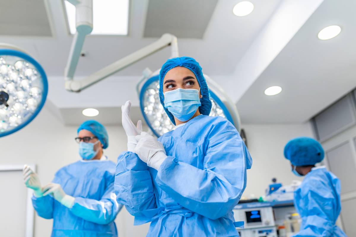 A surgical nurse practitioner puts on gloves while preparing for surgery.