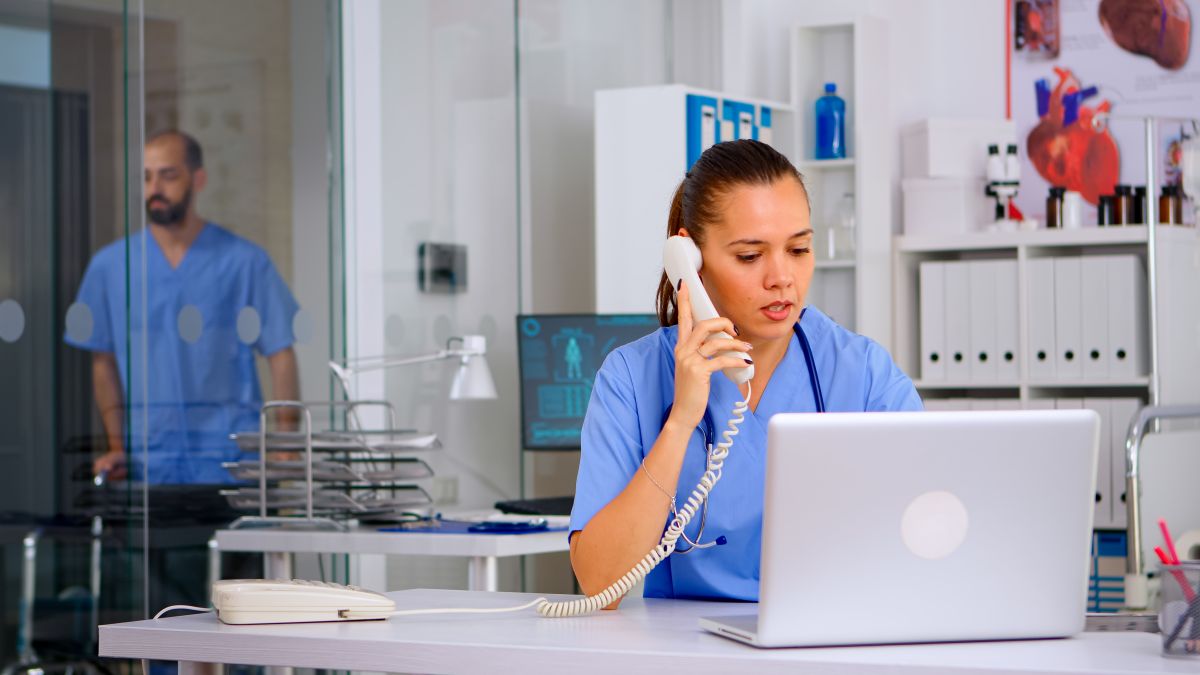 A telehealth nurse talks to a patient while looking at information on a laptop computer.