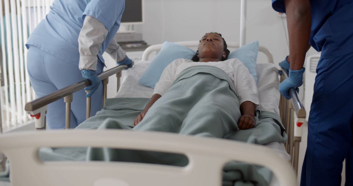 Two hospital staff carefully transport a patient.