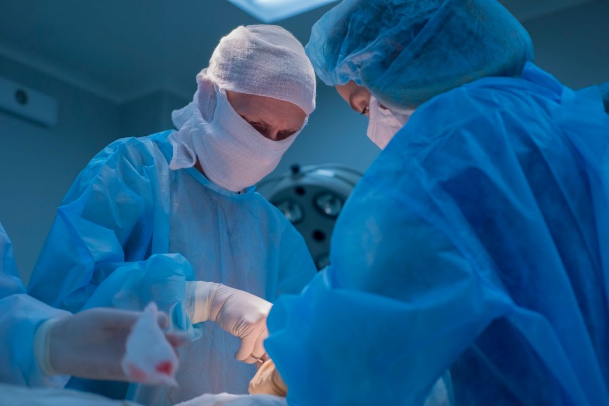 A urology nurse assists a physician with a surgical procedure.