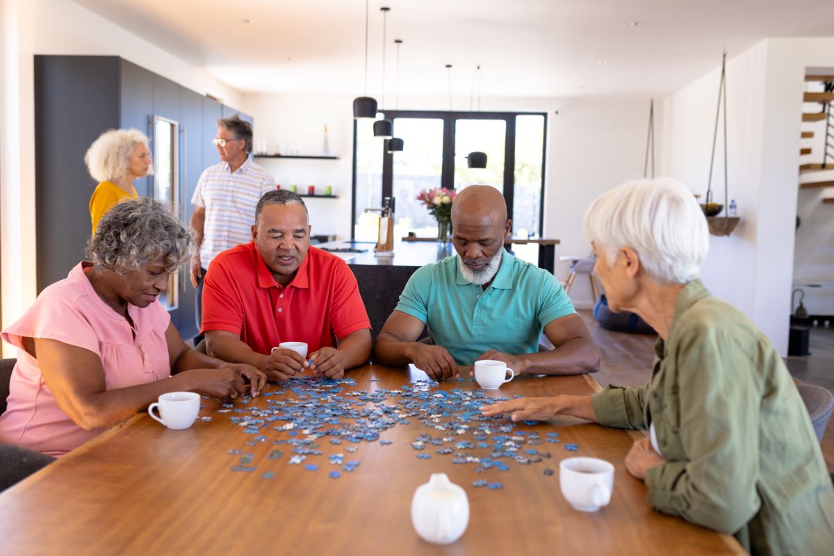 Residents at an assisted living facility, or "ALF," enjoying time together and working on a puzzle.