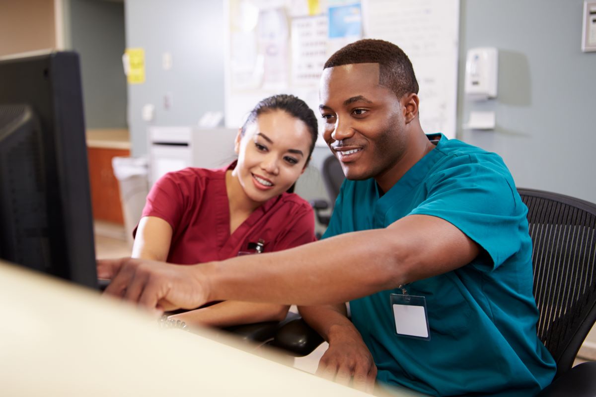 Two nurses sitting together at a work station, checking something on the EHR system.