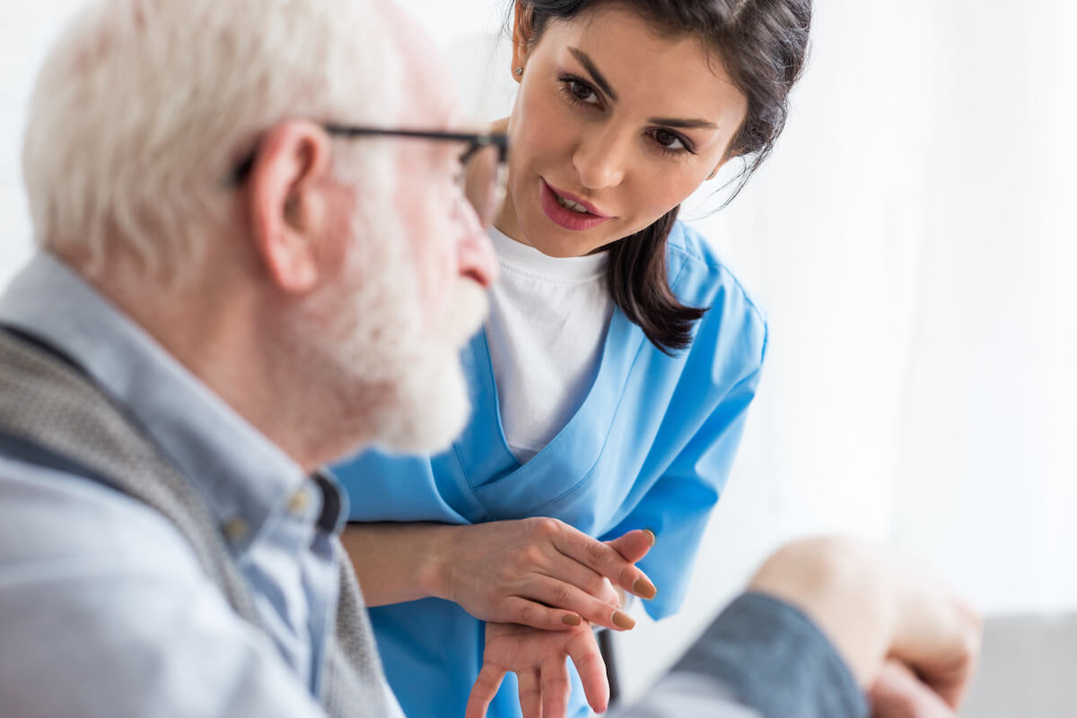 Young nurse talking with elderly resident in post-acute care.