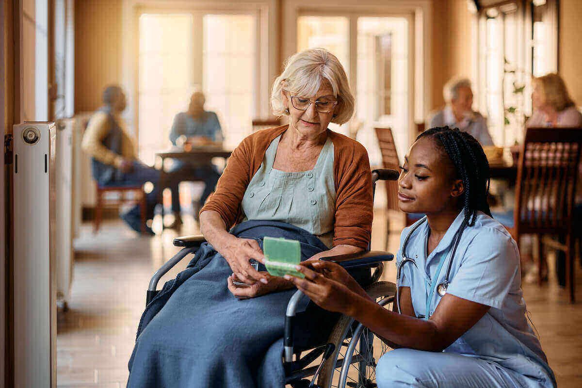 CMA dispensing pills to a senior patient in a wheelchair.