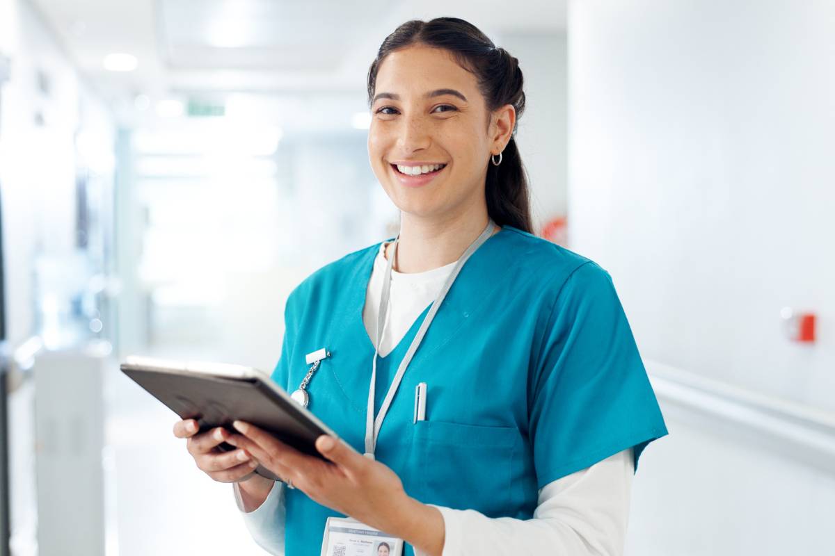 A nursing assistant poses for a photo while discussing the question, Where can CNAs work?