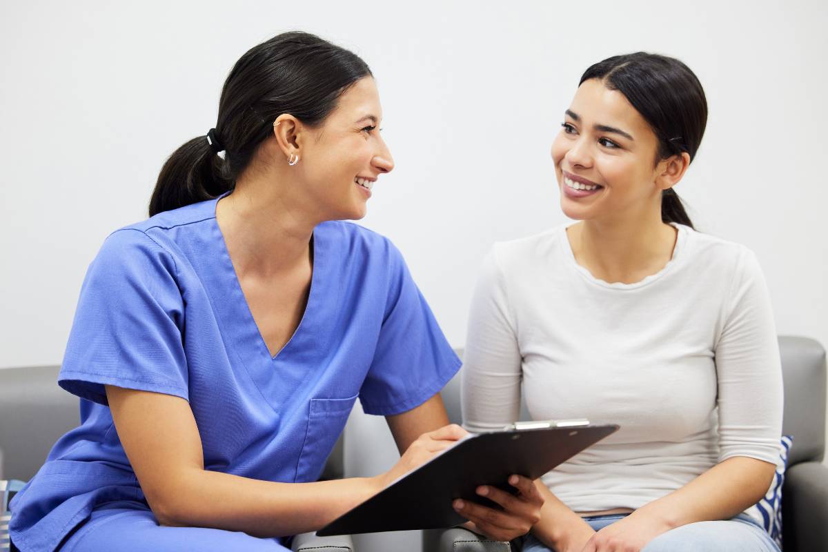 A women's health nurse practitioner helps a patient.